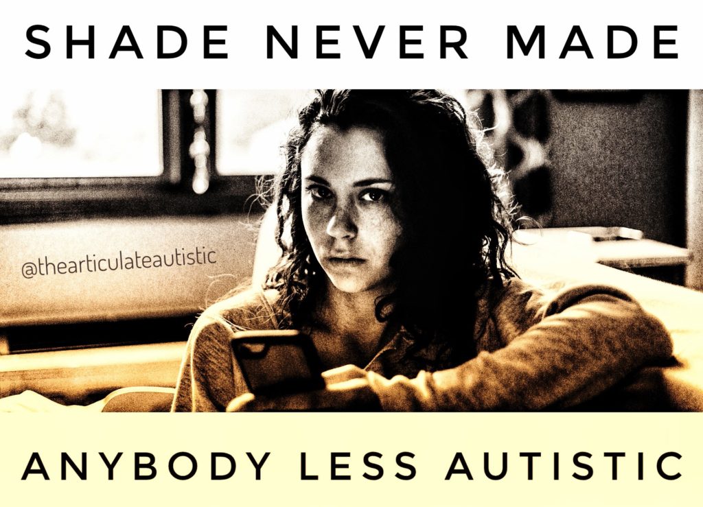 Woman with long, curly, dark hair holding her phone and looking directly at the camera with a serious and perhaps irritated expression with text that reads, "Shade Never Made Anybody Less Autistic".