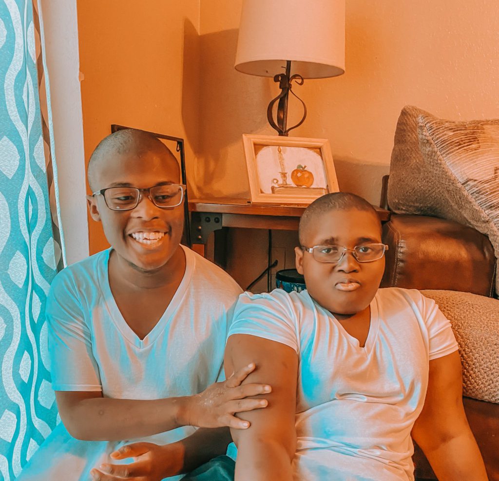 Two Black boys, brothers, both with glasses and white T-shirts