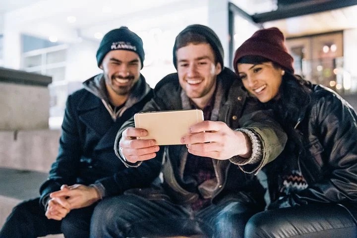 A group of 3 smiling young adults taking a selfie together.