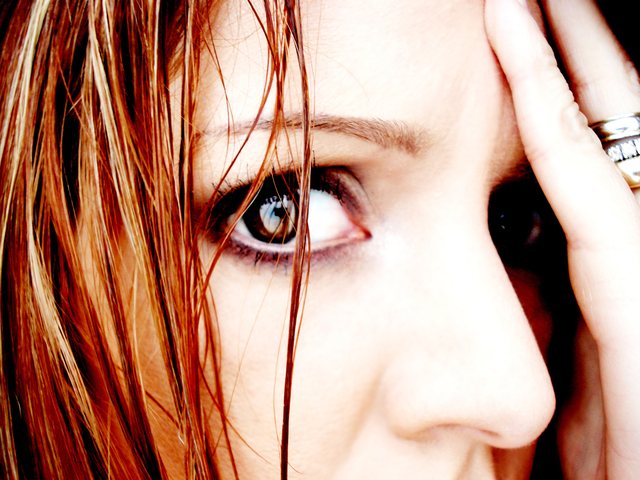 Close-up photo of a woman staring intently into the camera with what looks like deep anxiety and fear.