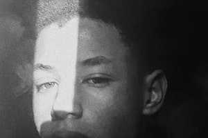 Black and white photo of an African American young man with the sun in his face.