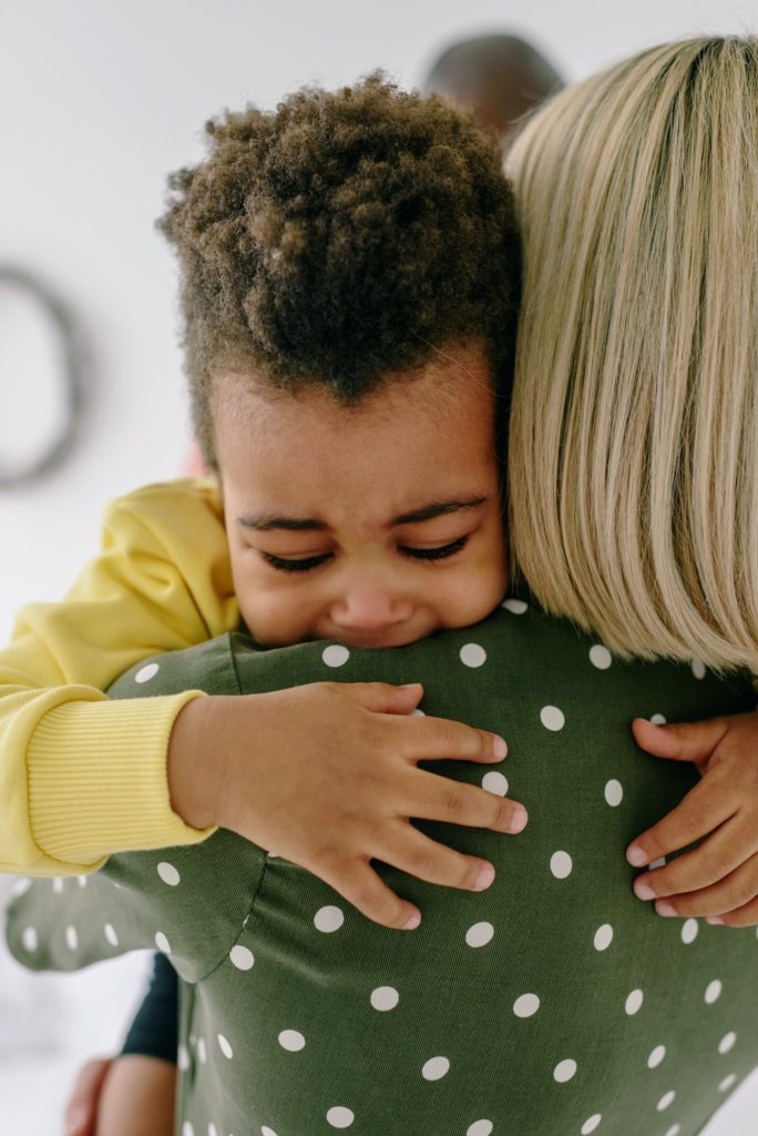 Adult picking up and comforting a child who is crying. 