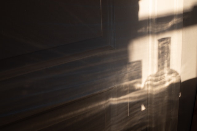 Artistic shot of the reflection of a glass bottle against a wall.