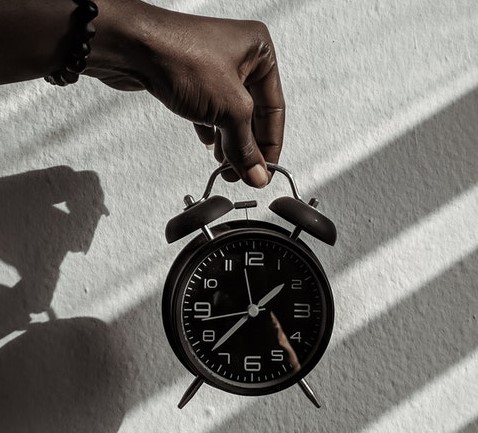 Photo of a hand holding an old-fashioned alarm clock. 