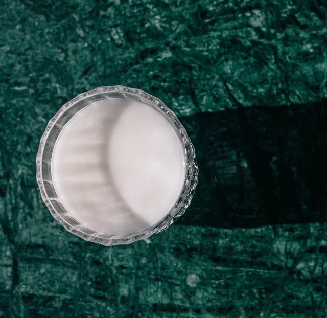A glass of milk on a green background. 