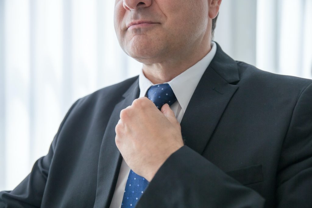 Close-up shot of a businessman fixing his blue tie. 